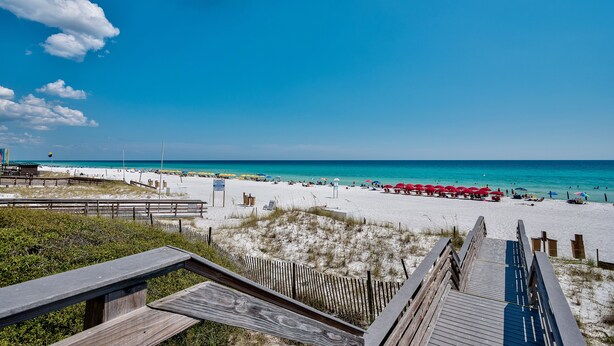 A beach with a wooden boardwalk leading to the shore, clear blue sky, and turquoise water. - Great Bay Views, Steps to Baytowne Wharf, Balcony, Beach Tram, Pool, Hot Tub. (Miramar Beach)