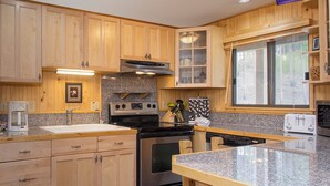Una cocina con armarios de madera, encimeras de granito, una estufa y un ventanal con vistas.