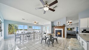 A spacious living area with a fireplace, dining table, and chairs. - Million dollar house on main river w/ million dollar view! Pool, Dock, Kayaks. (Crystal River)