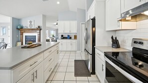 A modern kitchen with white cabinetry, a central island, a built-in oven, and a stainless steel range hood. - Million dollar house on main river w/ million dollar view! Pool, Dock, Kayaks. (Crystal River)