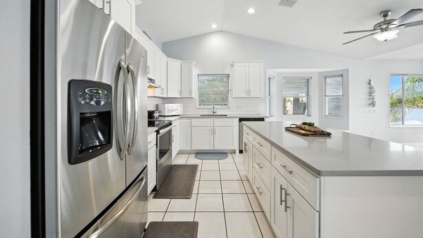 A modern kitchen with stainless steel appliances, white cabinetry, and a large island. - Million dollar house on main river w/ million dollar view! Pool, Dock, Kayaks. (Crystal River)