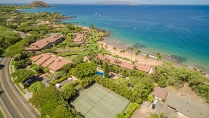 An aerial view of a coastal area with a tennis court, beach, and residential buildings. - Beachfront Condo B303 - December 13-27 Still Available! (Kihei)