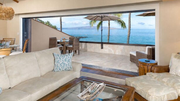 A living room with a sofa, coffee table, and a view of the ocean. - Beachfront Condo B303 - December 13-27 Still Available! (Kihei)
