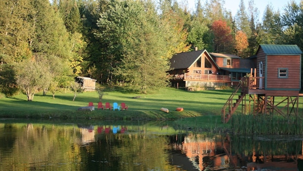 A cabin with a deck and a dock, surrounded by trees and a pond. - Spacious Log Cabin Perfect for Families and Pets (Glover)