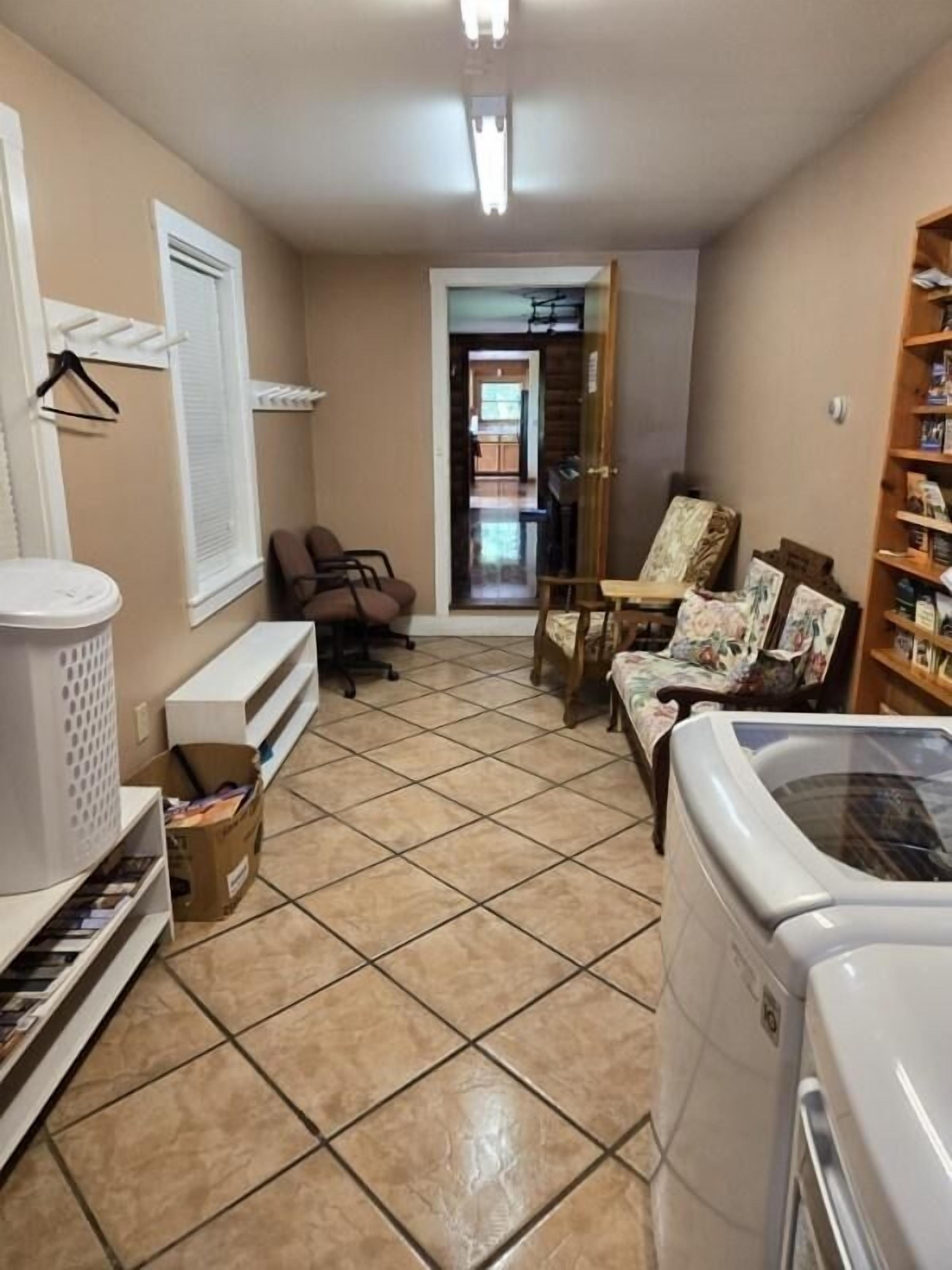 A laundry room with a washing machine, a drying rack, and a small table with chairs.