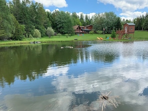 Una proprietà sul lago con un cottage in legno, una casa grande e una piccola casetta da gioco.