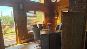 A cozy cabin interior with a wooden dining table, chairs, and a fireplace. - Spacious Log Cabin Perfect for Families and Pets (Glover)