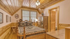 Ein Zimmer mit Holzwänden, einem Bett, einer Holzkommode und einer Tür.