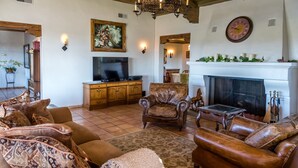 A cozy living room with a fireplace, leather sofas, a television, and a dining area.