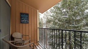 En träbalkong med två fåtöljer i rotting och en skylt med texten: ”Bergen och jag måste bege oss iväg, Winter Park, Colorado”.