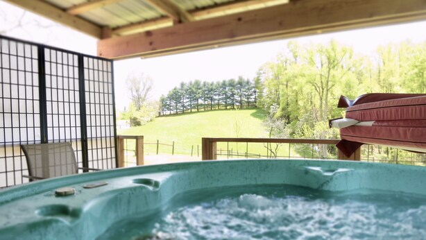 A hot tub with a view of a grassy area and trees.