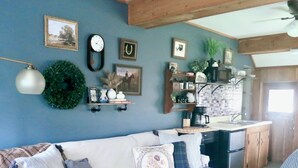 A cozy living room with a white sofa, a kitchen area with a refrigerator, and a dining table.