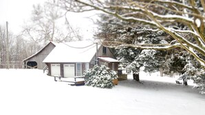 A wooden cabin with a snow-covered roof and a small porch.