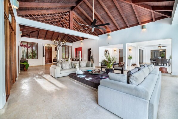 Un salón amplio con techo alto, chimenea y comedor con mesa y sillas.