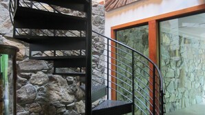 Una escalera de caracol con un muro de piedra y un amplio ventanal.