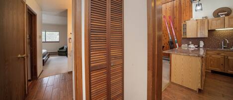 A hallway with wooden flooring leading to a kitchen area with wooden cabinets and a countertop.