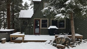 Eine Holzhütte mit roter Tür, umgeben von schneebedeckten Bäumen.