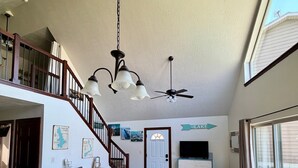 A spacious living area with a staircase, a dining table, a sofa, and a television.