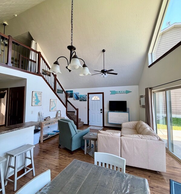 A spacious living area with a staircase, a dining table, a sofa, and a television.