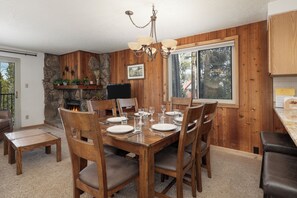 A wooden dining room with a fireplace, a stone wall, and a large window.