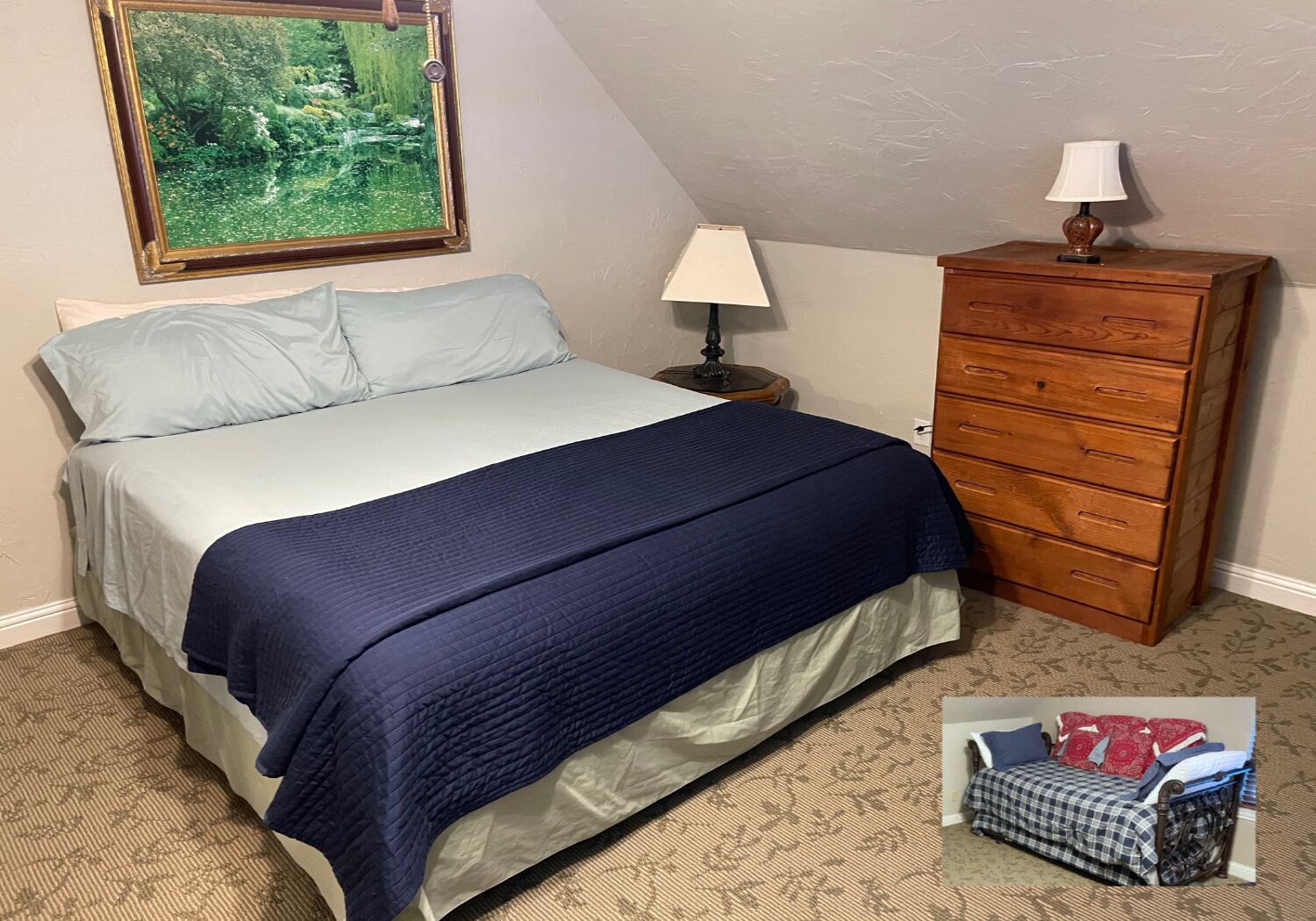 Une chambre à coucher avec un lit, une table de chevet avec une lampe, une commode et un tableau au mur.