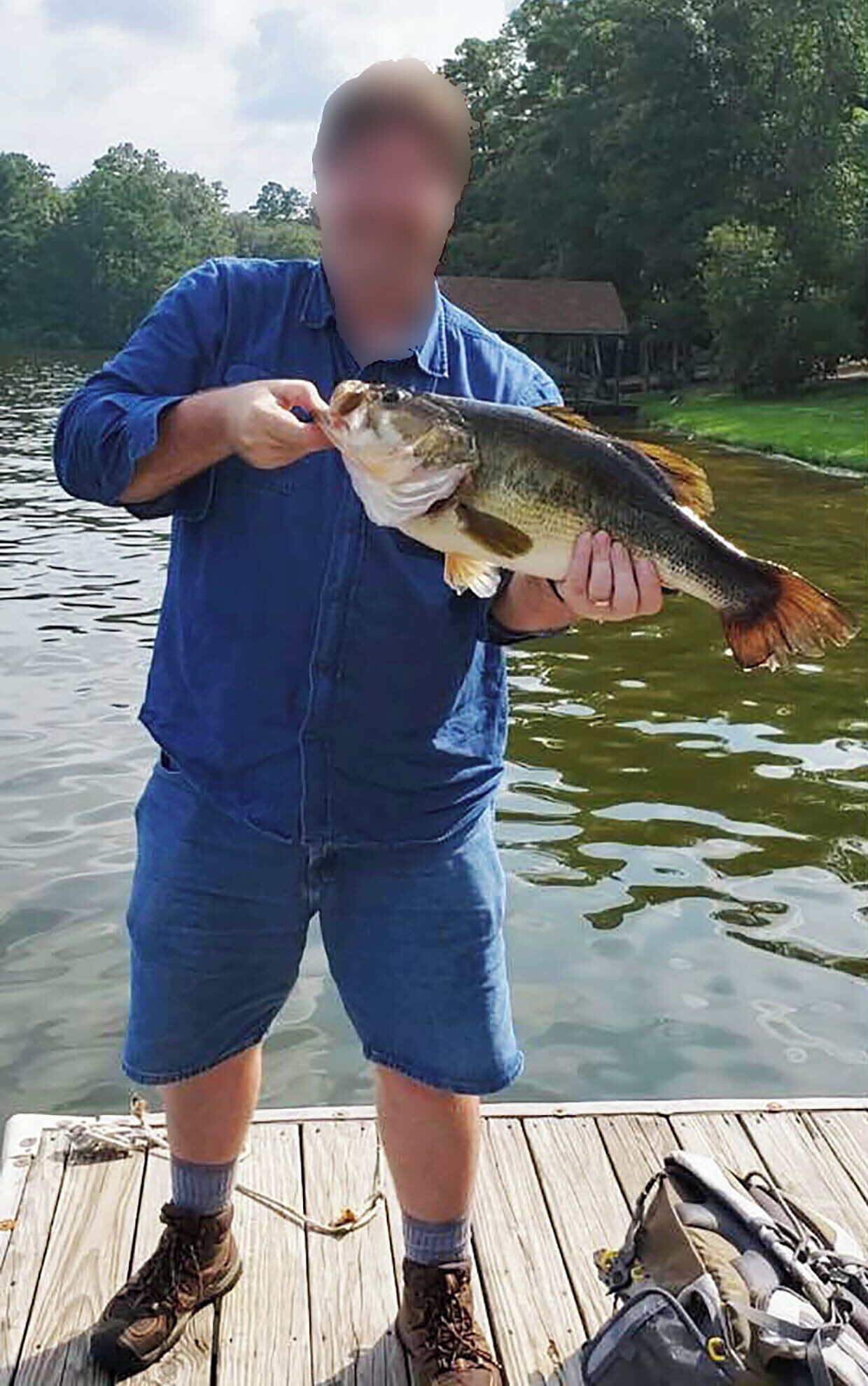 Une personne tenant un poisson sur un quai en bois, avec un bateau et du matériel de pêche en arrière-plan.