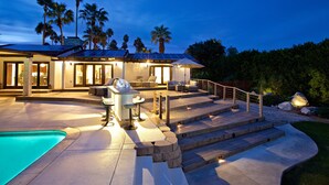 Une maison moderne dotée d’une piscine, d’un espace salon extérieur et d’une terrasse bien éclairée.