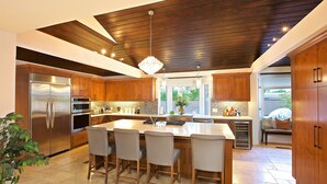 Une cuisine moderne avec des meubles en bois, des appareils en acier inoxydable et un grand îlot central doté de tabourets de bar.
