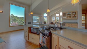Una cocina moderna con una isla grande, horno empotrado y abundante luz natural proveniente de ventanas amplias.