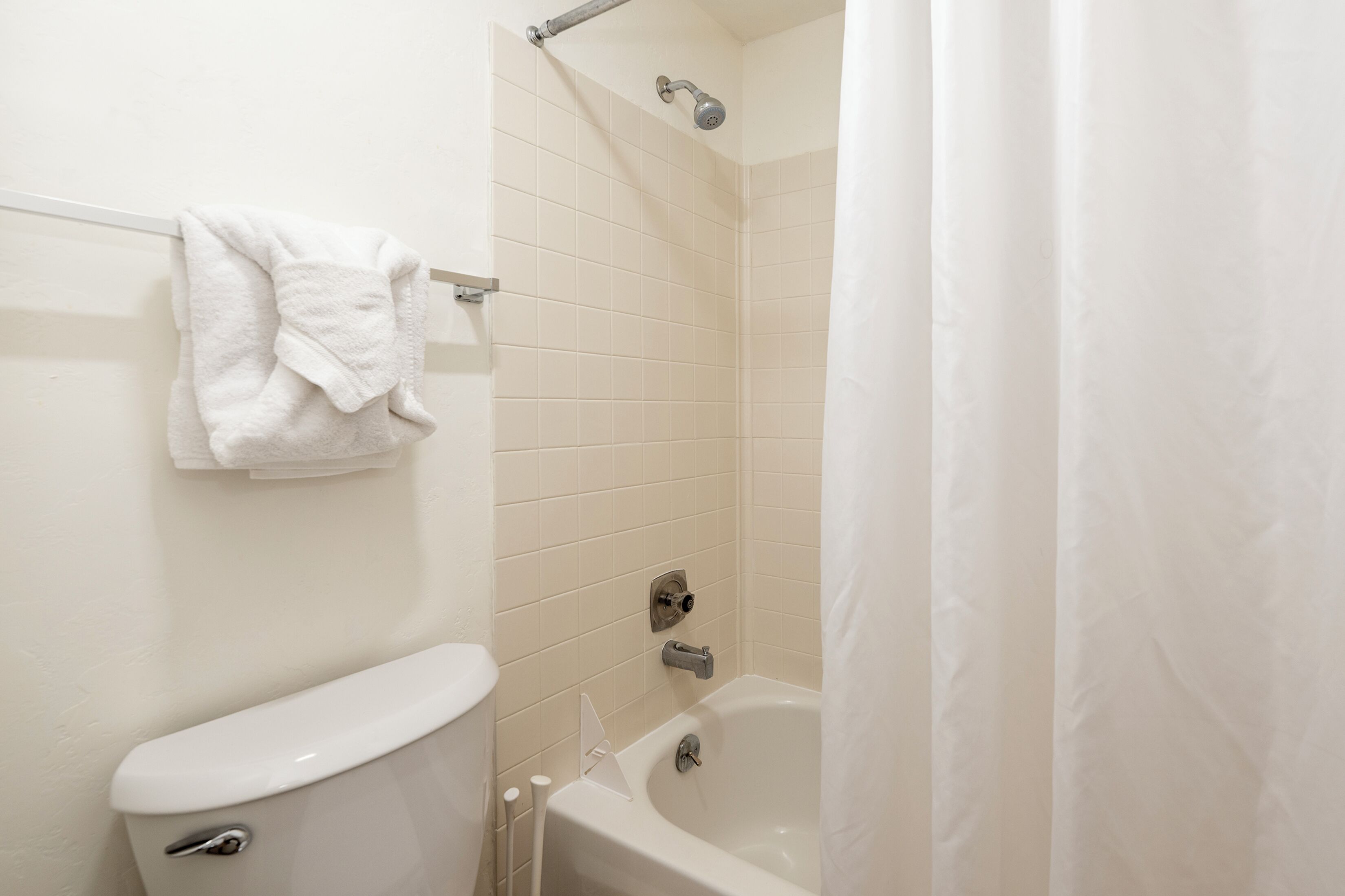 A bathroom with a toilet, a bathtub, and a shower curtain.