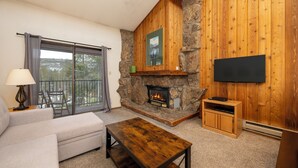 A living room with a stone fireplace, a flat-screen TV, a sofa, and a coffee table.