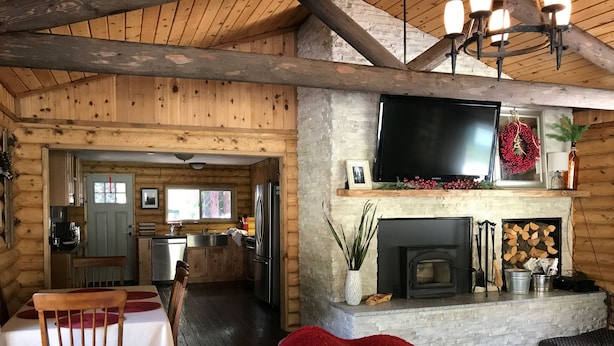 Ein gemütliches Blockhaus-Interieur mit Essbereich, Küche, Wohnzimmer und Kamin.
