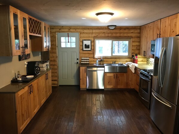 A wooden cabin-style kitchen with a stainless steel refrigerator, a dishwasher, and a sink.