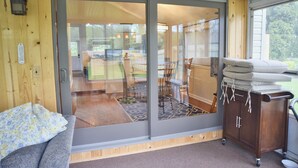Una habitación con puerta de cristal corredera que da a un patio exterior, un armario de madera con toallas y un banco acolchado.