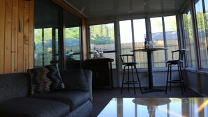 Una habitación acogedora con un sofá, una mesita y una ventana con vistas a una terraza de madera.