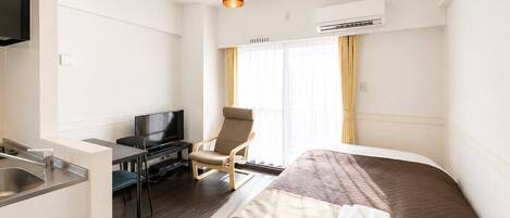 Une chambre d’hôtel équipée d’un lit, d’un bureau, d’une chaise, d’une télévision et d’un appareil de climatisation.