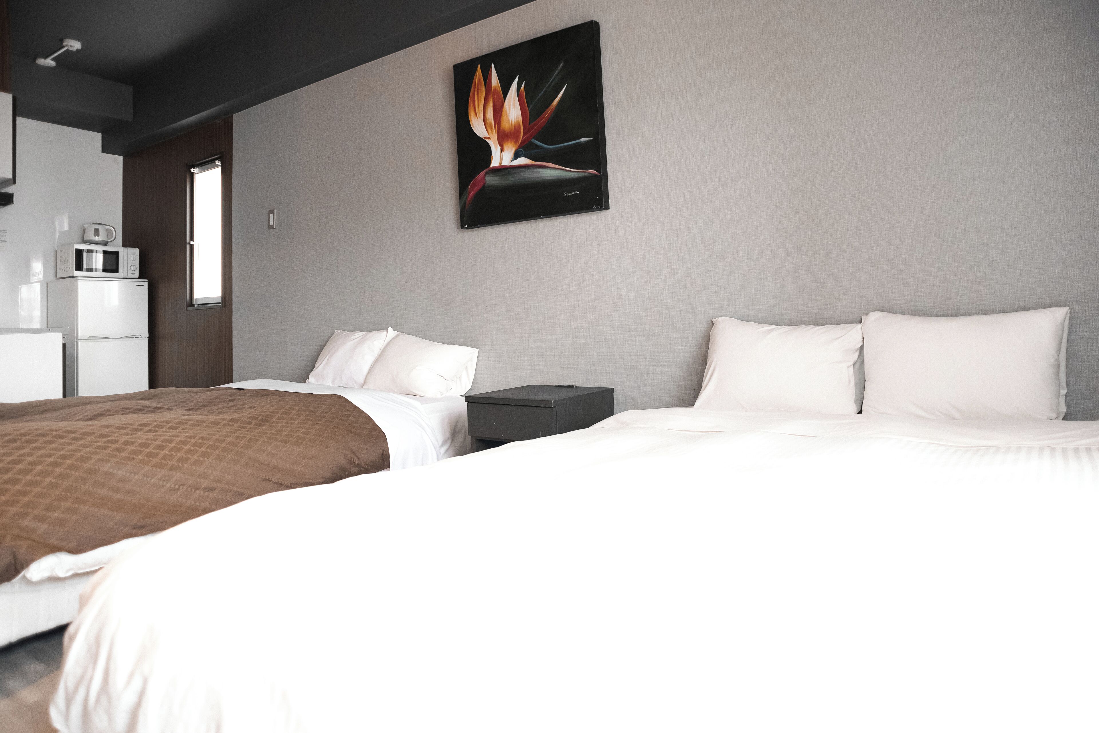Habitación de hotel con cama, mesita de noche, microondas y refrigerador.