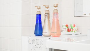 A bathroom with three bottles of shampoo, conditioner, and soap on a counter. - Mr. Kinjo inn D-buil (Naha)