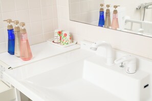 Ein Badezimmer mit einem weißen Waschbecken, einem Spiegel und drei Shampoo-Flaschen.