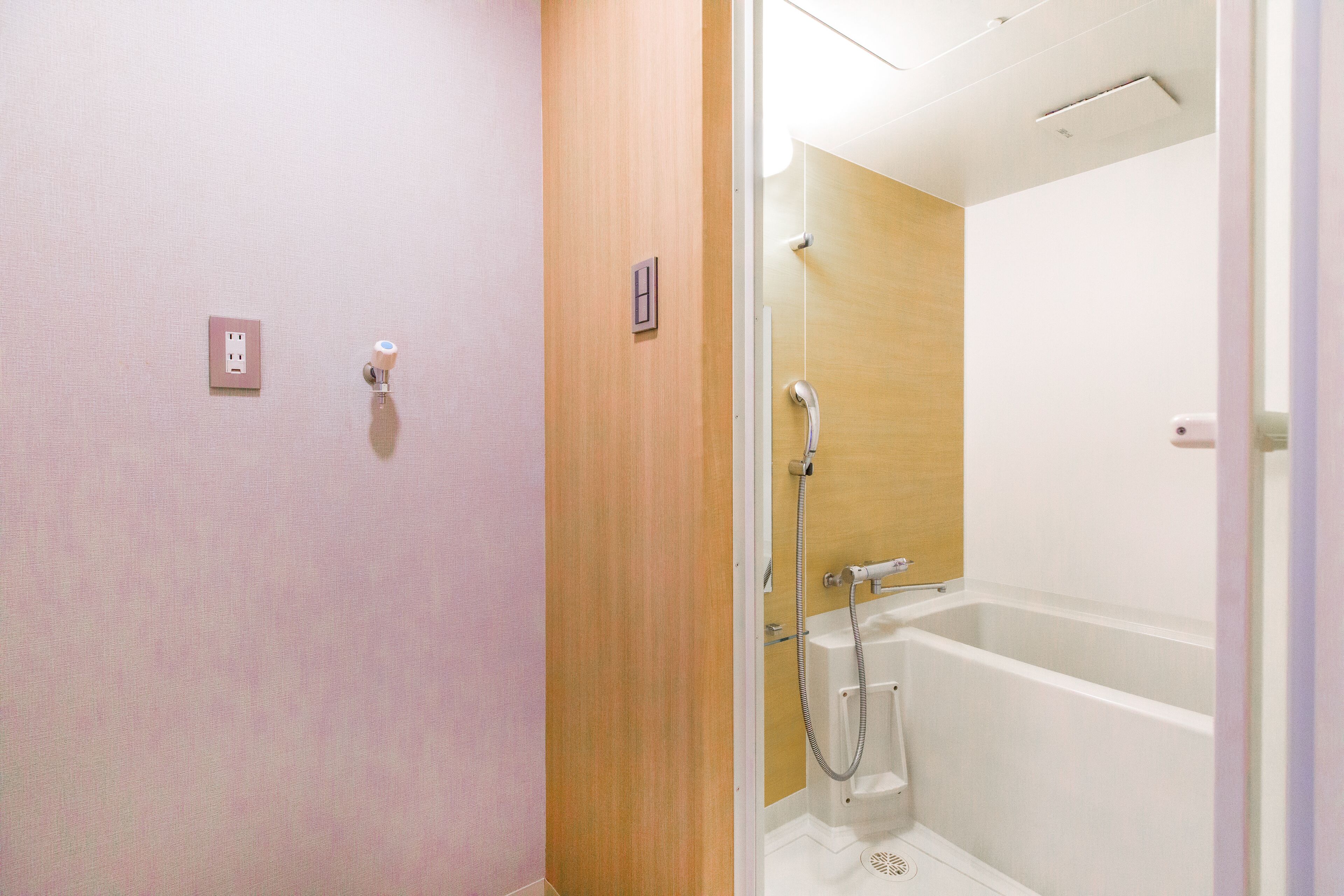 Un bagno con una porta in legno, una doccia e una vasca da bagno bianca.