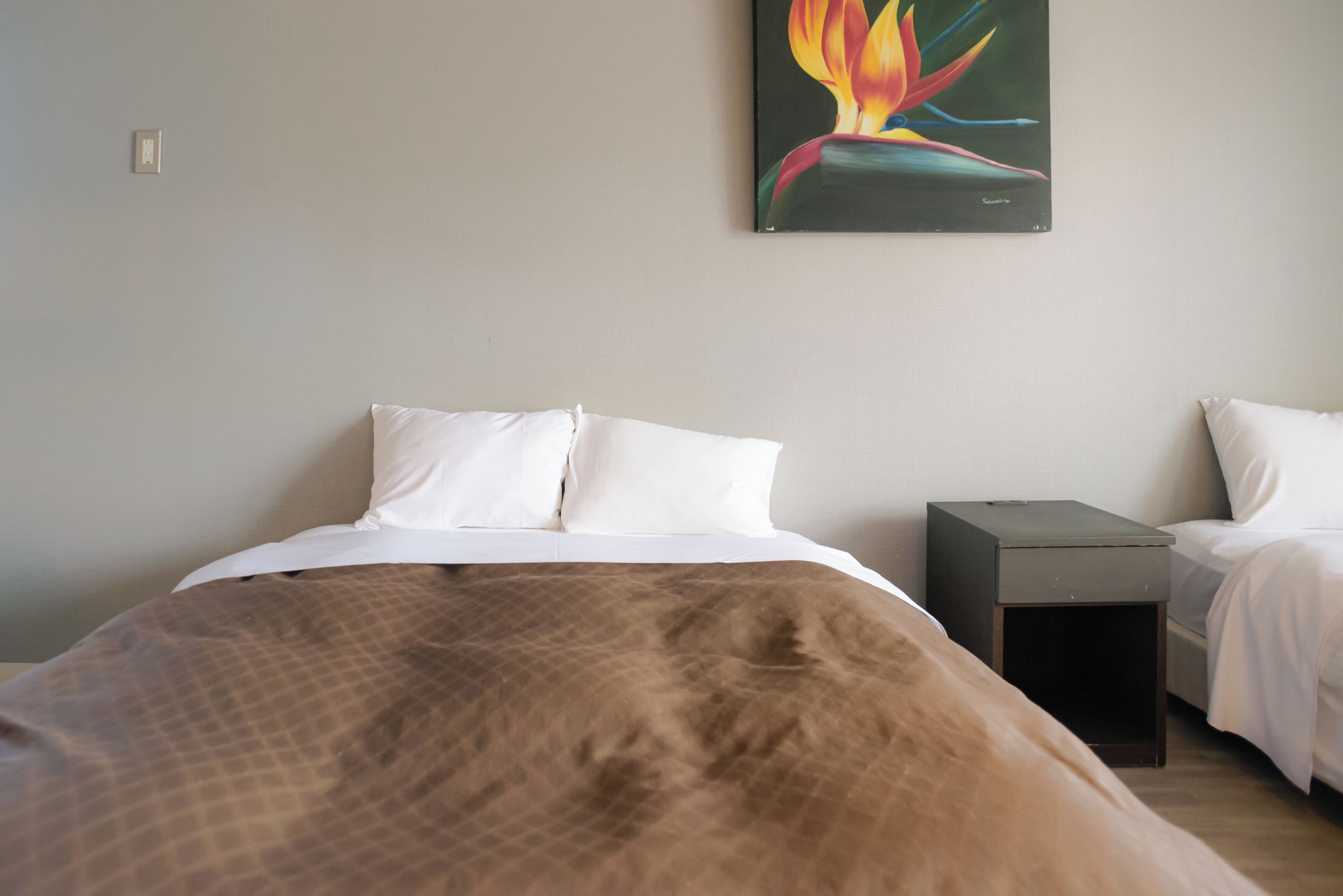 A bedroom with a large bed, a nightstand, and a painting on the wall.