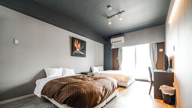 A modern hotel room with a large bed, a smaller bed, a desk, and a chair. - Mr. Kinjo inn D-buil (Naha)