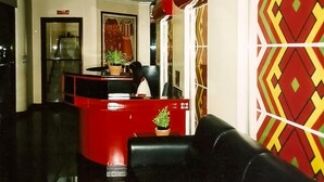 Een receptie met een rode balie, zwarte lederen zitplaatsen en een potplant.