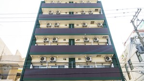 Een meerlaags gebouw met balkons, airconditioners en zichtbare elektriciteitskabels.