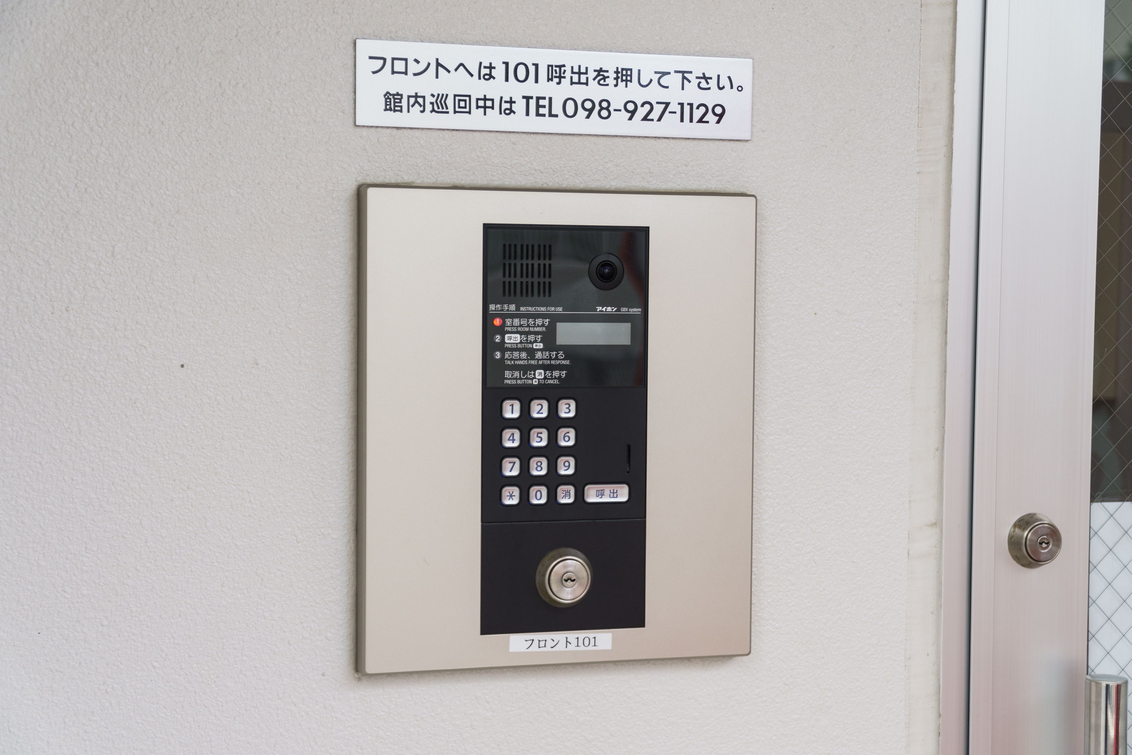 A security keypad with instructions in Japanese, a lock, and a door with a metal mesh pattern.