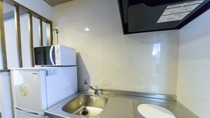 Una cocina compacta con un lavamanos de acero inoxidable, un microondas y un refrigerador.