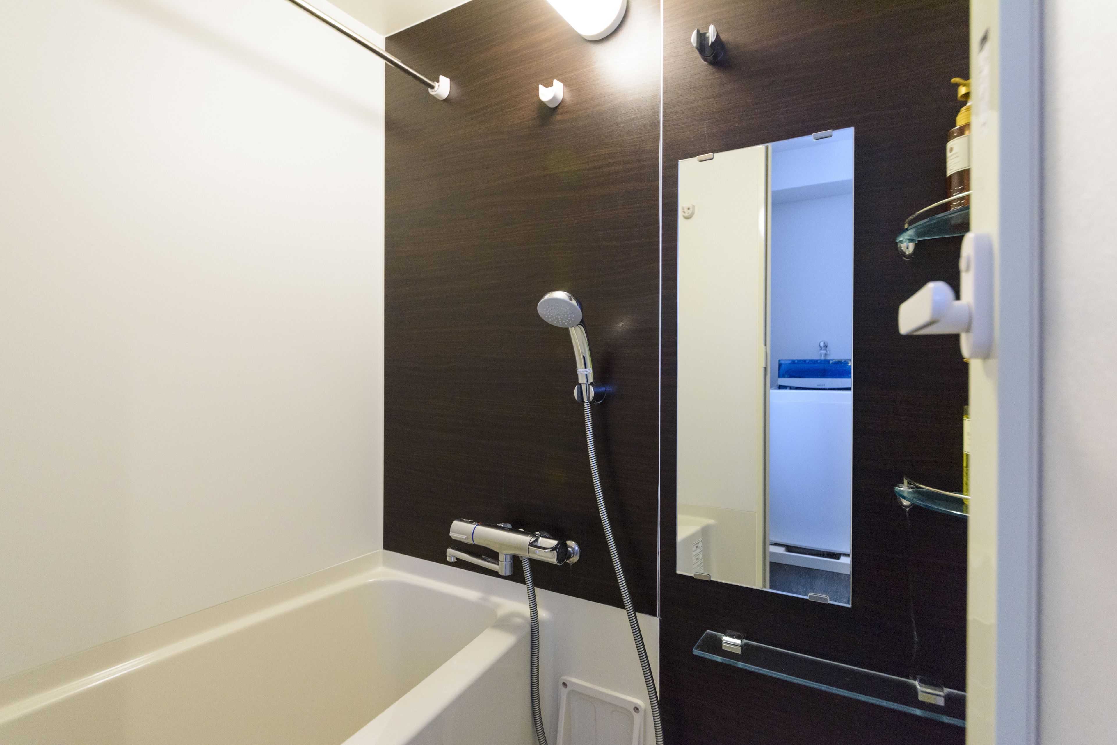 A modern bathroom with a bathtub, a shower, and a large mirror.