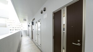 Un pasillo estrecho con un balcón a un lado, que conduce a un conjunto de puertas.