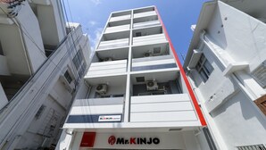 Un edificio de varios pisos con un llamativo letrero de 'Mr. KINJO' en la planta baja.