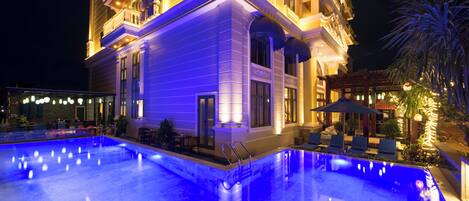 Una piscina al aire libre, sombrillas, sillones reclinables de piscina